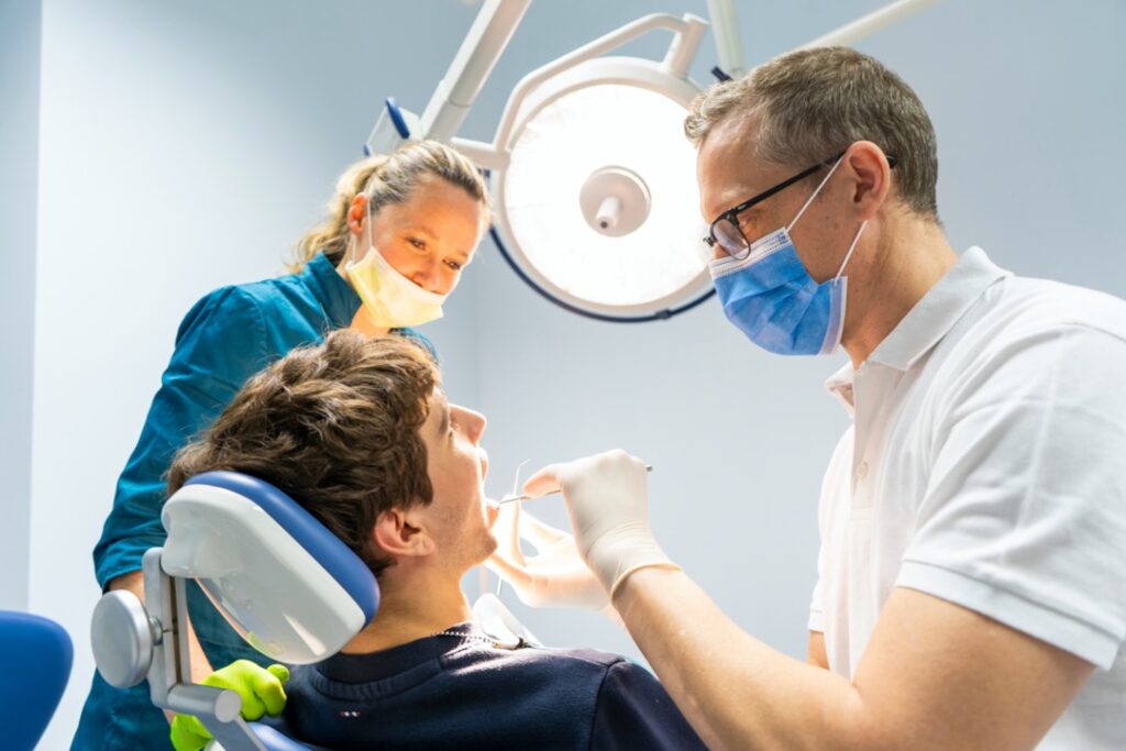 Dentist cleaning young man's teeth 