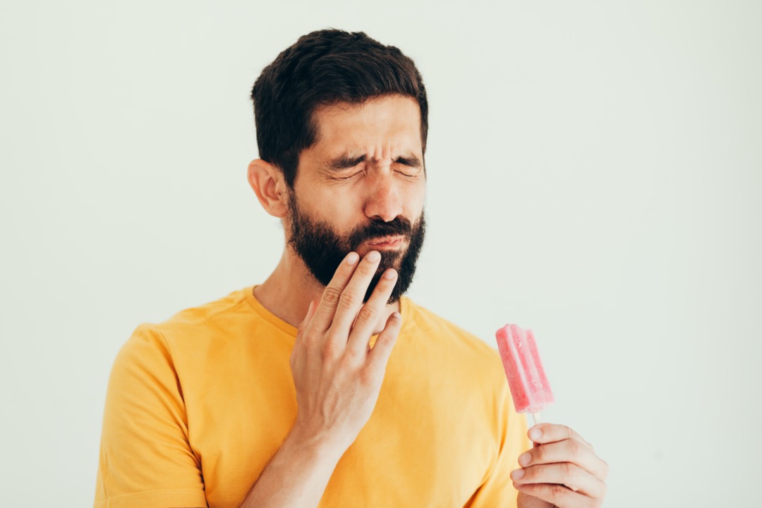 Man experiencing tooth sensitivity from cold popsicle